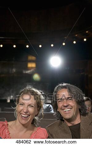 Stock Image - A couple laughing in a movie theater. Fotosearch