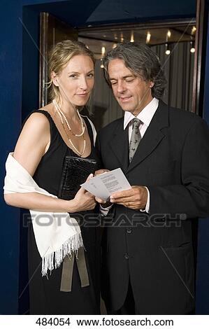 A couple standing with tickets in a theater foyer View Large Photo Image Picture - A couple standing with tickets in a theater foyer. Fotosearch