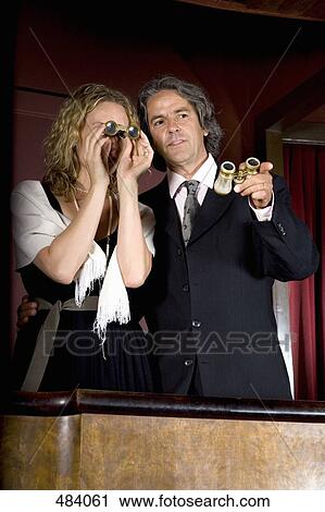 Stock Image - A couple using binoculars in a theater box. Fotosearch