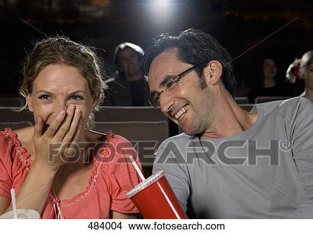 Picture - A mid adult couple laughing in a movie theater. Fotosearch