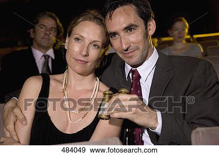 Stock Photo - A mid adult couple sitting in a theater. Fotosearch