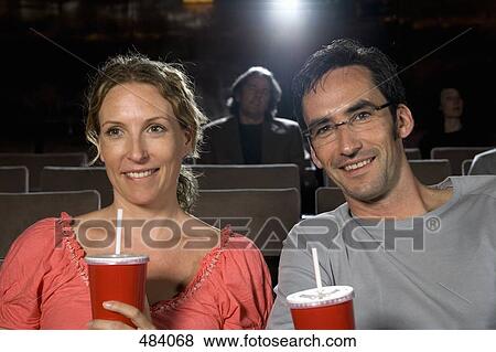 Stock Photo - A mid adult couple sitting together in a movie theater. Fotosearch