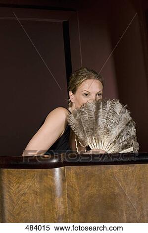 A woman sitting in a theater box and holding a feather fan in front of her face View Large Photo Image Stock Photography - A woman sitting in a theater box and holding a feather fan in front of her face. Fotosearch