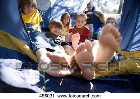 Stock Image - A woman and a group of children piled up in a tent. Fotosearch