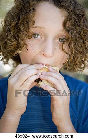 A young boy eating a sausage in a bread roll View Large Photo Image Picture - A young boy eating a sausage in a bread roll. Fotosearch