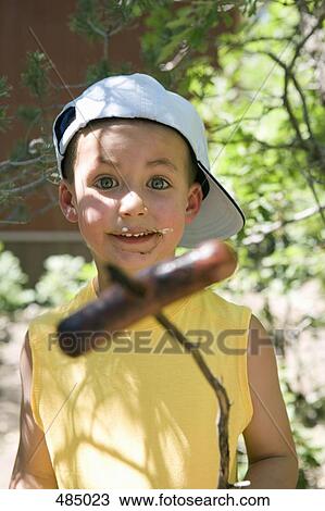 A young boy holding a cooked sausage on a stick View Large Photo Image Stock Image - A young boy holding a cooked sausage on a stick. Fotosearch