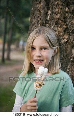 Stock Photo - A young girl eating toasted marshmallow. Fotosearch