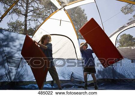 Stock Image - Two boys playing with inflatable mattresses in a tent. Fotosearch