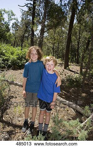 Stock Image - Two boys standing together in a forest. Fotosearch