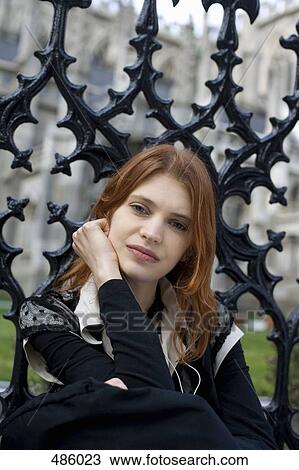 Stock Image - A portrait of a young woman in front of an iron gate. Fotosearch