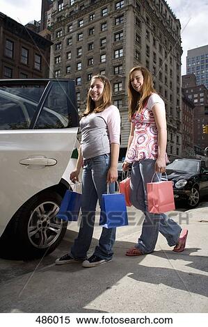 Two adolescent girls boarding a car with shopping bags View Large Photo Image Stock Photography - Two adolescent girls boarding a car with shopping bags. Fotosearch