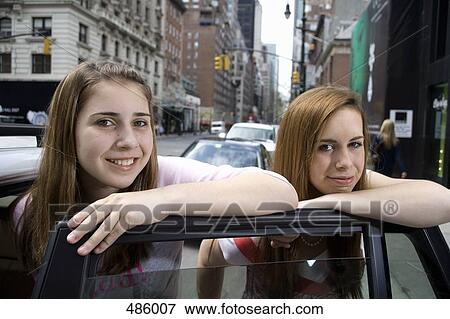 Stock Photo - Two adolescent girls leaning on a car door. Fotosearch