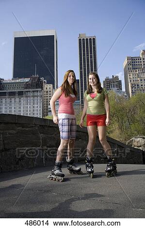 Picture - Two adolescent girls on inline skates in a park. Fotosearch