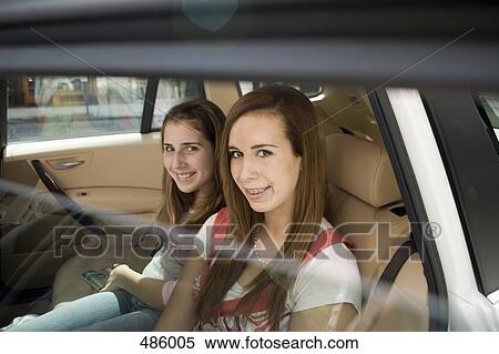 Two adolescent girls sitting in the back seat of a car View Large Photo Image Stock Photography - Two adolescent girls sitting in the back seat of a car. Fotosearch