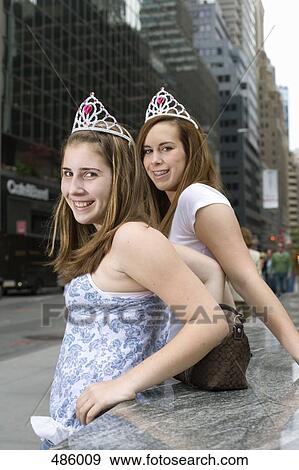 Two adolescent girls wearing tiaras on a city street View Large Photo Image Stock Photo - Two adolescent girls wearing tiaras on a city street. Fotosearch