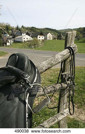 A saddle and reins hanging over a wooden fence View Large Photo Image Stock Photo - A saddle and reins hanging over a wooden fence. Fotosearch