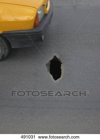 A car driving near a hole in the street View Large Photo Image Stock Image - A car driving near a hole in the street. Fotosearch