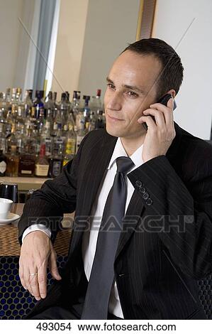 A businessman on his phone in bar View Large Photo Image Picture - A businessman on his phone in bar. Fotosearch
