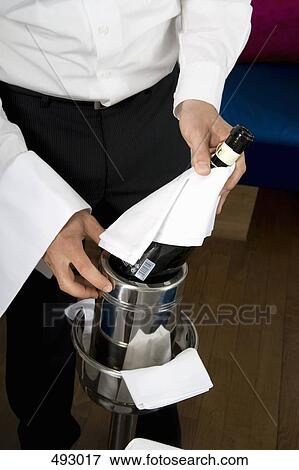 A waiter putting a wine bottle into a cooler View Large Photo Image Stock Photo - A waiter putting a wine bottle into a cooler. Fotosearch