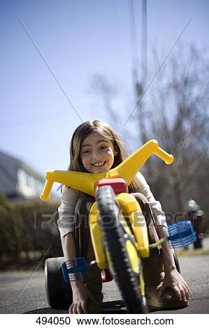 Stock Image - A girl sitting on a tricycle. Fotosearch