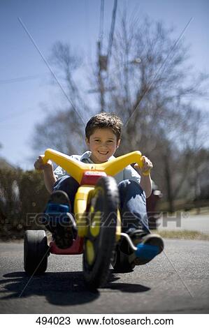A young boy riding a tricycle View Large Photo Image Stock Image - A young boy riding a tricycle. Fotosearch