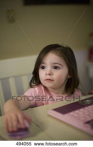 A young girl sitting at a table with a toy laptop View Large Photo Image Stock Photography - A young girl sitting at a table with a toy laptop. Fotosearch
