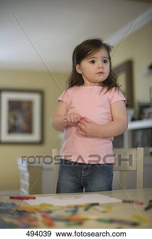 A young girl standing on a chair at a table View Large Photo Image Stock Photo - A young girl standing on a chair at a table. Fotosearch