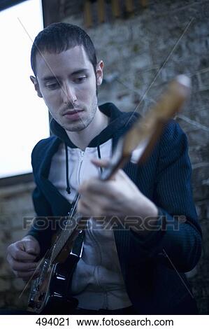 A young man playing an electric guitar View Large Photo Image Stock Image - A young man playing an electric guitar. Fotosearch