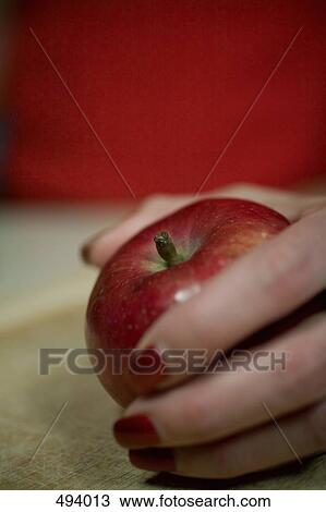 Detail of a woman holding an apple on a cutting board View Large Photo Image Stock Image - Detail of a woman holding an apple on a cutting board. Fotosearch