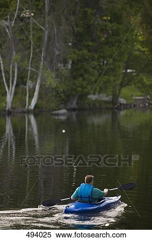 Stock Photography - Rear view of a man kayaking on a river. Fotosearch
