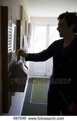 Stock Photo - A man inserting a time card into a time clock. Fotosearch