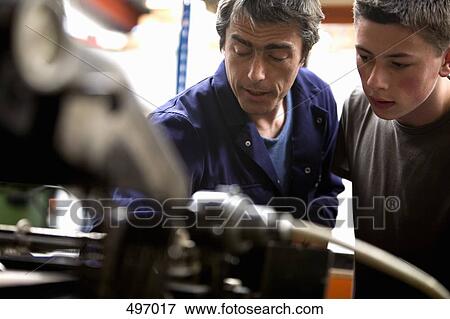 A man training a young man in a printing factory View Large Photo Image Stock Photo - A man training a young man in a printing factory. Fotosearch