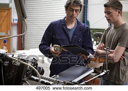 A man training a young man in a printing factory View Large Photo Image Stock Photography - A man training a young man in a printing factory. Fotosearch