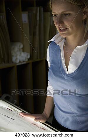 Stock Photo - A woman looking at material on a light box. Fotosearch