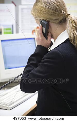 A woman sitting at a desk and holding a telephone receiver View Large Photo Image Stock Image - A woman sitting at a desk and holding a telephone receiver. Fotosearch