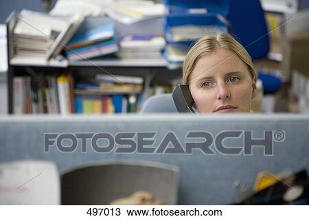 A woman using a phone in an office cubicle View Large Photo Image Stock Image - A woman using a phone in an office cubicle. Fotosearch