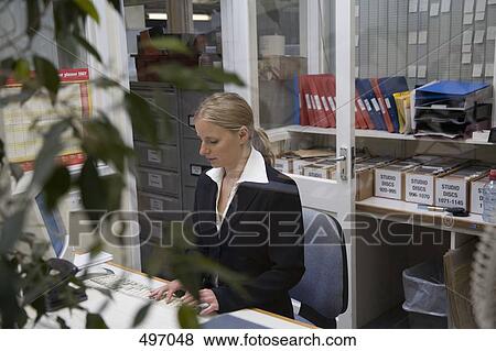 Stock Photo - A woman working at a desk in an office. Fotosearch