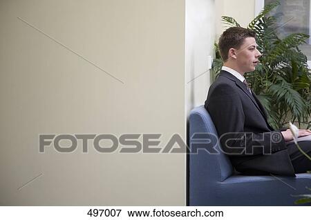 A young businessman sitting in an office reception View Large Photo Image Stock Photo - A young businessman sitting in an office reception. Fotosearch