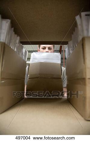 Picture - A young man storing a box of paperwork. Fotosearch