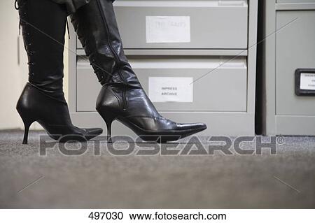 Detail of a woman wearing high heel boots standing next to filing cabinets View Large Photo Image Stock Image - Detail of a woman wearing high heel boots standing next to filing cabinets. Fotosearch