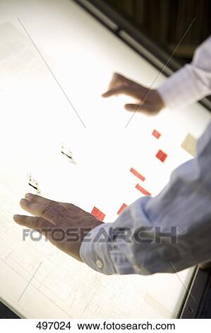 Detail of two businessmen leaning over a light box View Large Photo Image Picture - Detail of two businessmen leaning over a light box. Fotosearch