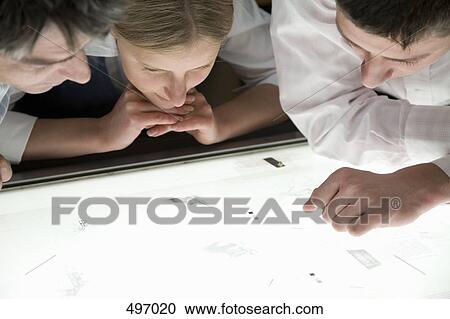 Three colleagues leaning over a light box View Large Photo Image Stock Image - Three colleagues leaning over a light box. Fotosearch