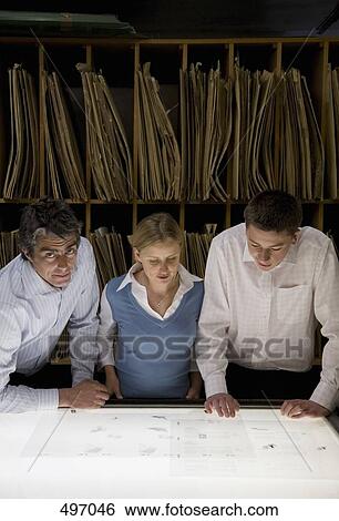 Three colleagues leaning over a light box View Large Photo Image Stock Photograph - Three colleagues leaning over a light box. Fotosearch