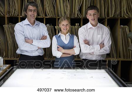 Three colleagues standing side by side behind a light box View Large Photo Image Stock Photo - Three colleagues standing side by side behind a light box. Fotosearch