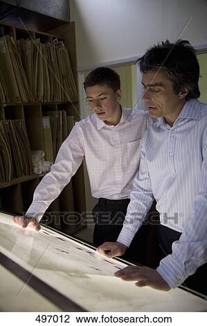 Two businessmen standing in front of a light box View Large Photo Image Stock Image - Two businessmen standing in front of a light box. Fotosearch