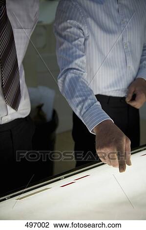 Two businessmen standing over a light box View Large Photo Image Stock Image - Two businessmen standing over a light box. Fotosearch