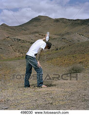 A man standing in an arid landscape and pouring water over his head View Large Photo Image Stock Image - A man standing in an arid landscape and pouring water over his head. Fotosearch