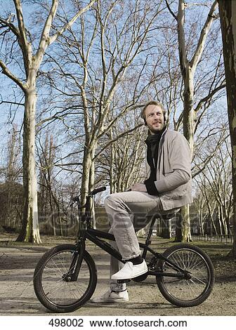 A man wearing headphones and sitting on a BMX in a park View Large Photo Image Stock Image - A man wearing headphones and sitting on a BMX in a park. Fotosearch