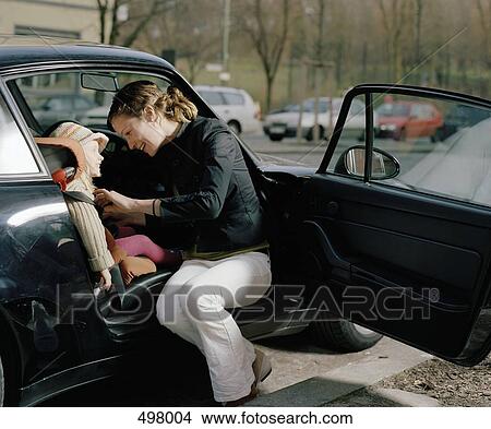 A woman putting a safety belt on her daughter View Large Photo Image Picture - A woman putting a safety belt on her daughter. Fotosearch
