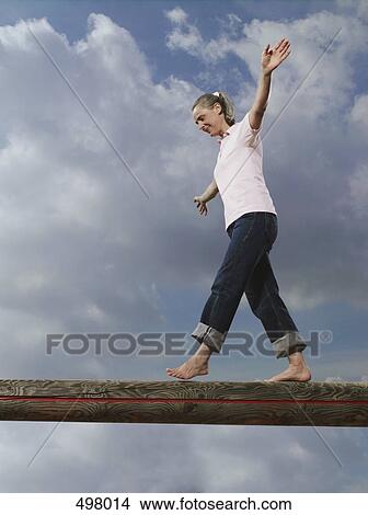 A woman walking along a wooden log View Large Photo Image Picture - A woman walking along a wooden log. Fotosearch